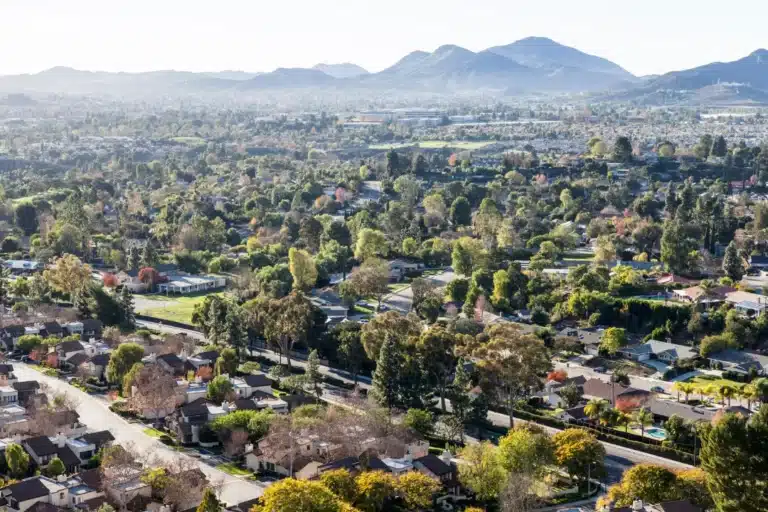 Aerial view of suburban neighborhoods and rolling hills in Thousand Oaks, California, showcasing residential greenery and scenic landscape.