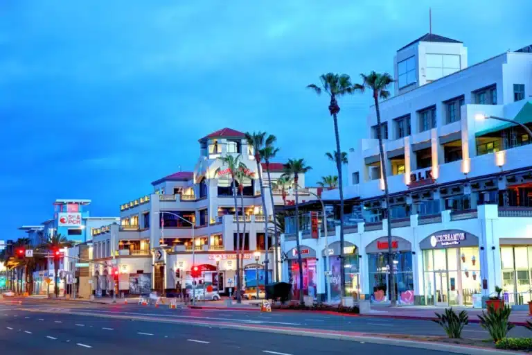 Downtown Huntington Beach nightlife scene with shops, palm trees, and illuminated buildings near Main Street.