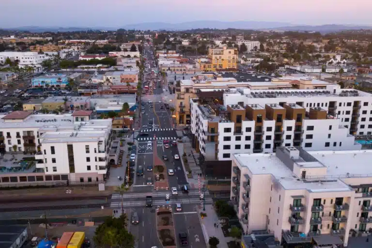 Oceanside coastal city view with sandy beaches, ocean horizon, palm trees, and nearby residential areas in Southern California.