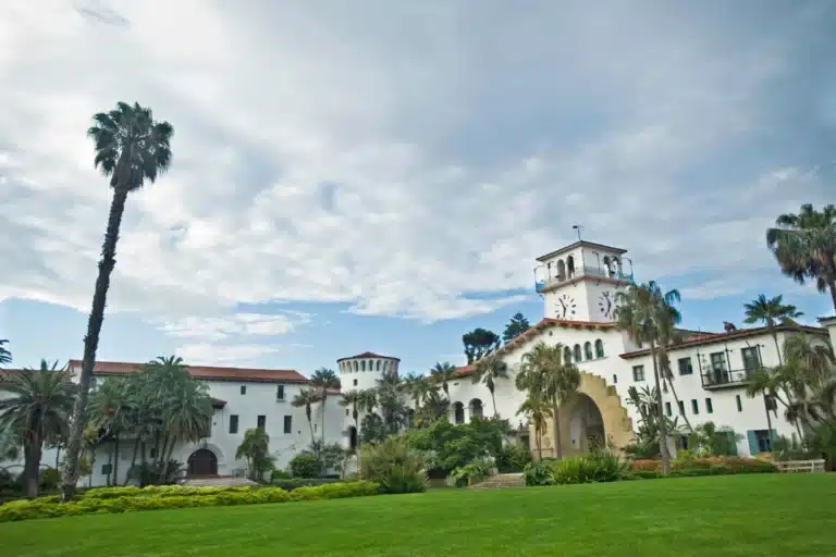 Santa Barbara Spanish-style architecture with white stucco buildings, red tile roofs, and palm trees under a clear sky
