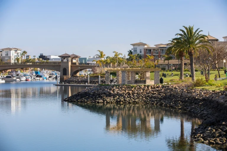 Oxnard, CA cityscape with marina waterfront, colorful sunset sky, and scenic coastal neighborhoods near the Pacific Ocean.