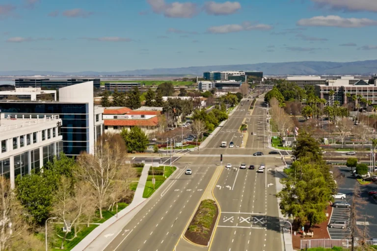 Aerial view of a bustling street, showcasing cars, pedestrians, and surrounding buildings.