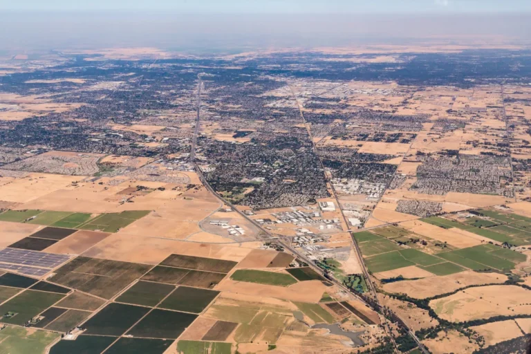 Aerial view of a cityscape with buildings, streets, and greenery visible from an airplane window.