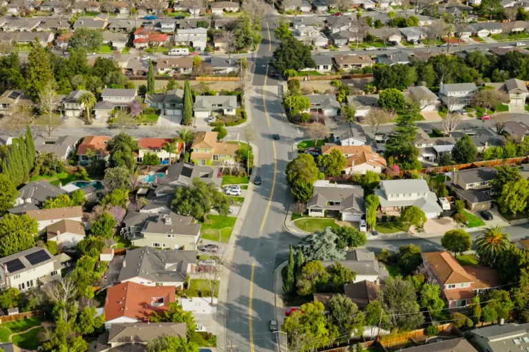 Aerial view of a residential neighborhood in Sunnyvale, CA with suburban streets, lush greenery, and distant hills in the background.